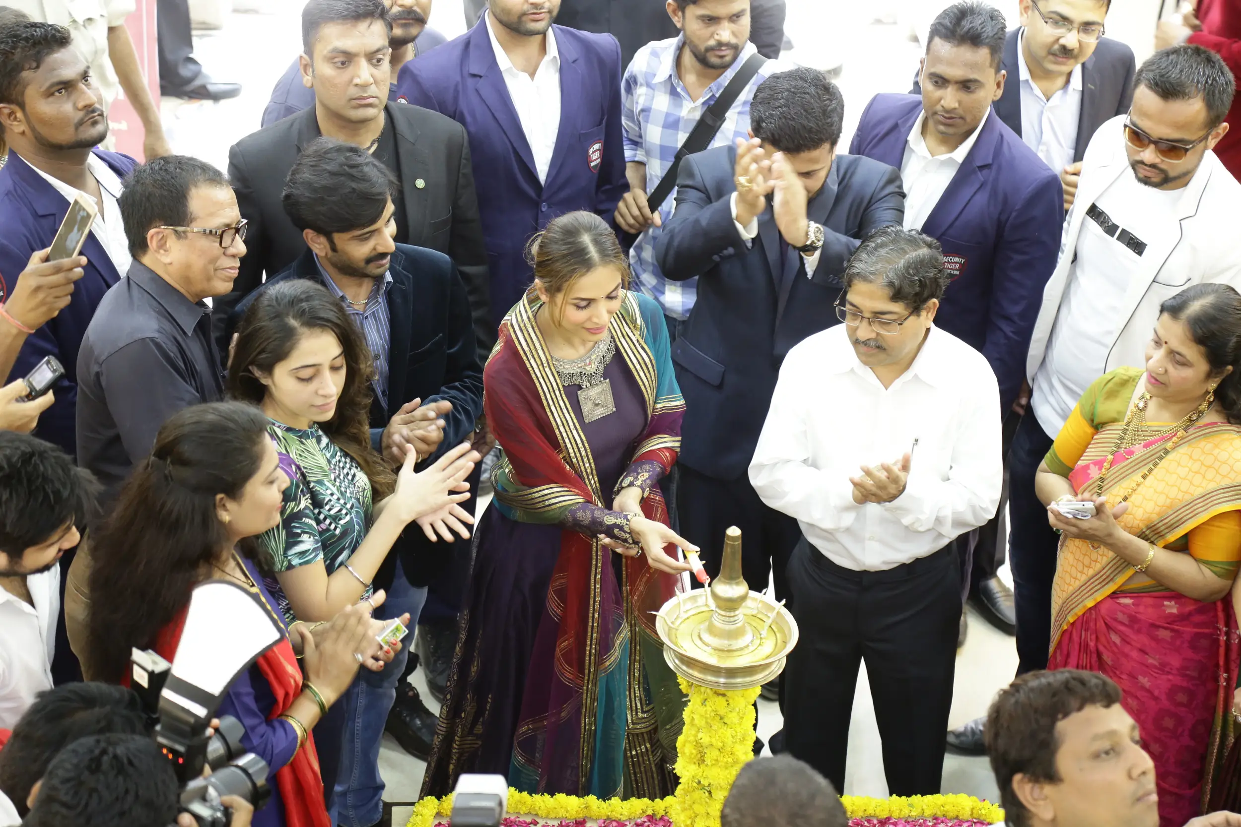 Men lighting ceremonial lamp at event with ITT banner in background
